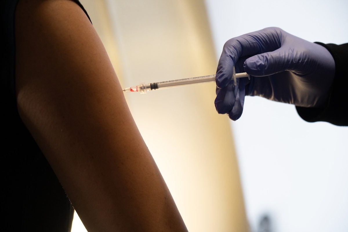 Gloved person giving an injection in a patient's upper arm