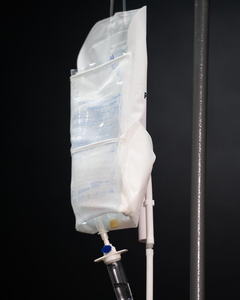 IV drip bag hanging on a stand against a dark background